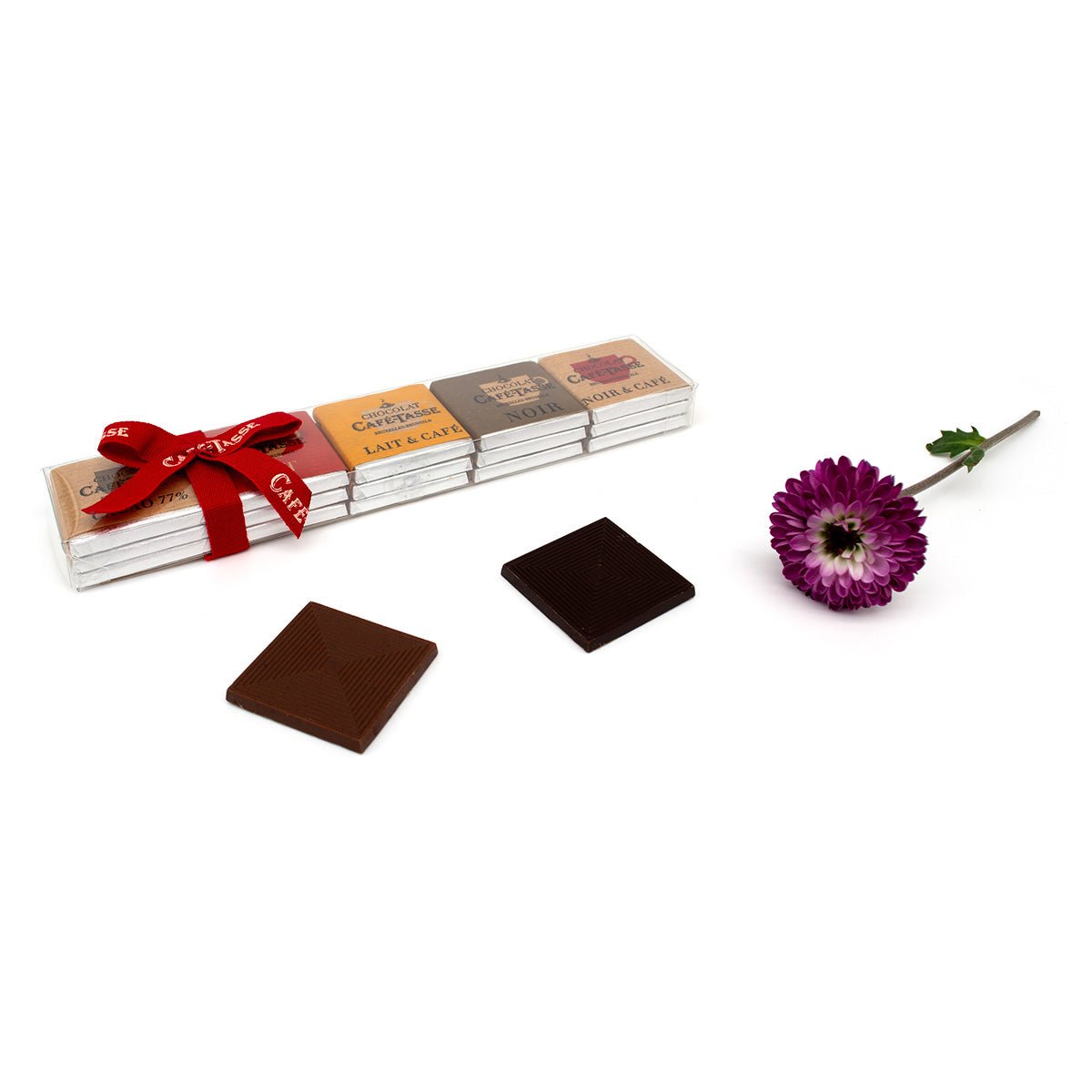 Set of chocolate bars with a red ribbon, two chocolate squares, and a purple flower on a white background