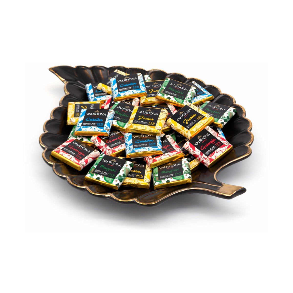 Assorted Valrhona chocolate squares on a decorative black plate with a white background