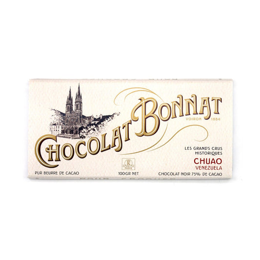 A 100g bar of Chocolat Bonnat Chuao Venezuelan chocolate, wrapped in an off-white paper wrapper with gold and black lettering and a black ink illustration of a cathedral.
