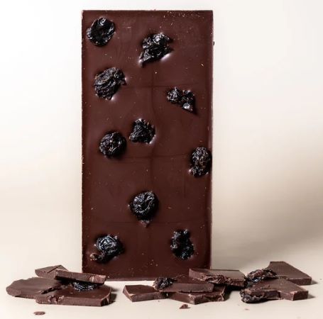 Dark chocolate bar with dried cherries on a light background