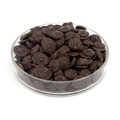 Glass bowl filled with dark chocolate wafers on a white background