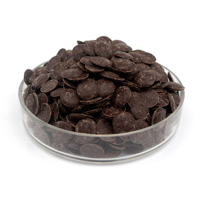 Glass bowl filled with dark chocolate wafers on a white background