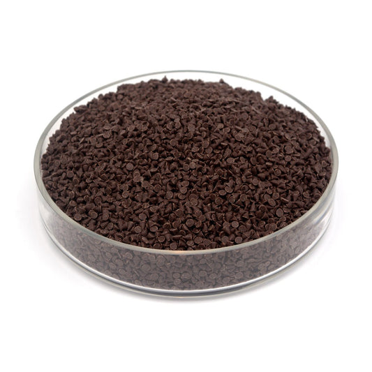 Brown small chocolate chips in a clear glass container on a white background