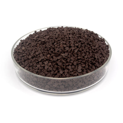Glass bowl filled with small dark brown chocolate chips on a white background