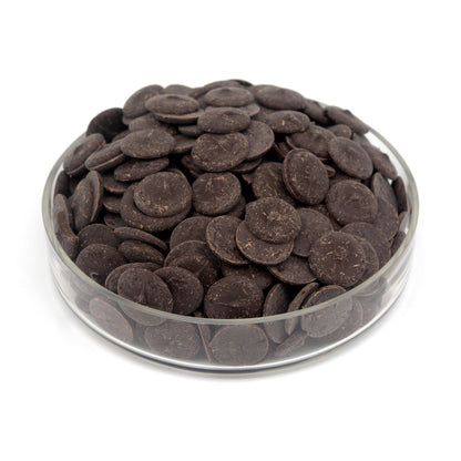 Glass bowl filled with dark chocolate wafers on a white background