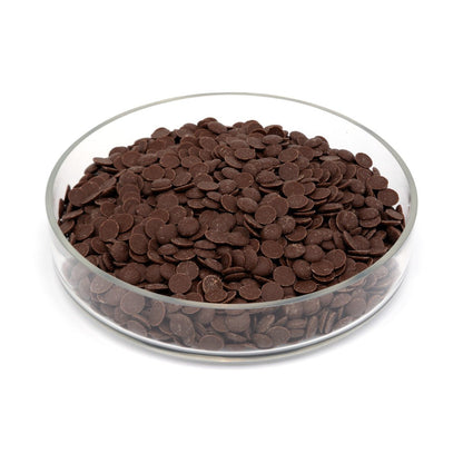 Glass bowl filled with brown chocolate discs on a white background