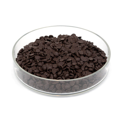 Glass bowl filled with dark chocolate discs on a white background