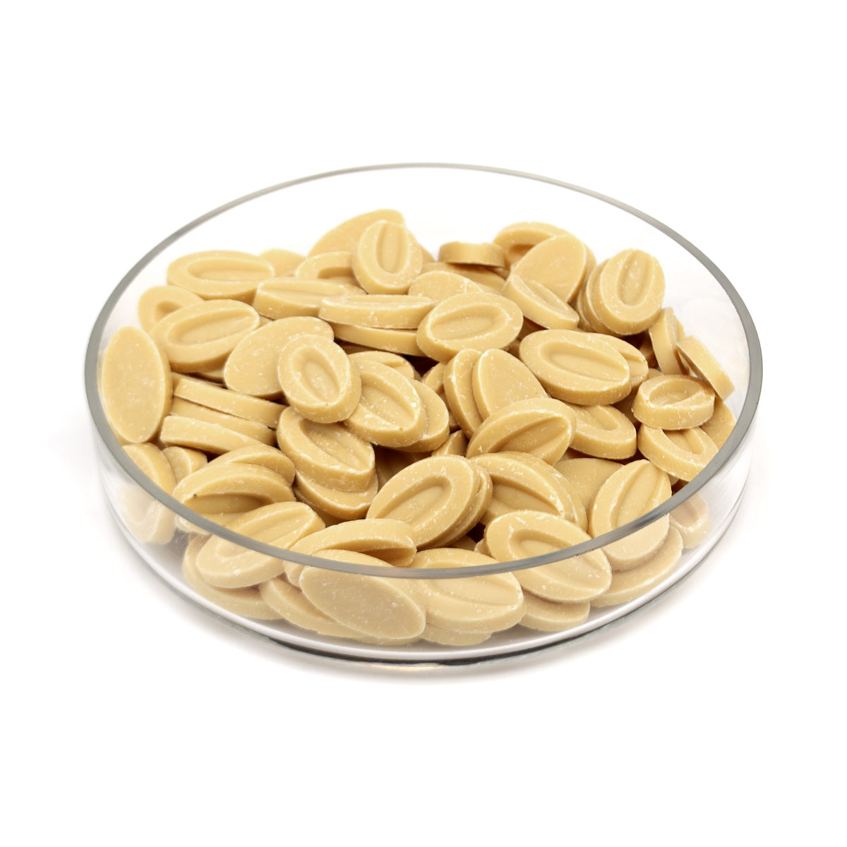 A clear glass bowl filled with small, oval, light tan chocolate discs, photographed on a clean white background.