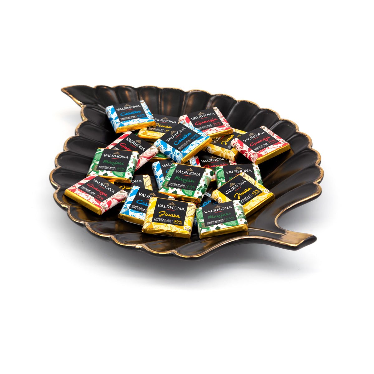 Assorted Valrhona chocolate squares on a decorative black plate with a white background
