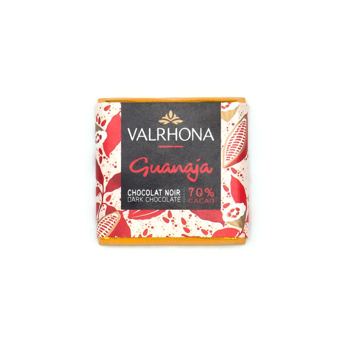 A single Valrhona Guanaja chocolate napolitain wrapped in a cream-colored paper sleeve with red and gold cacao pod illustrations and a black center label, photographed on a plain white background.