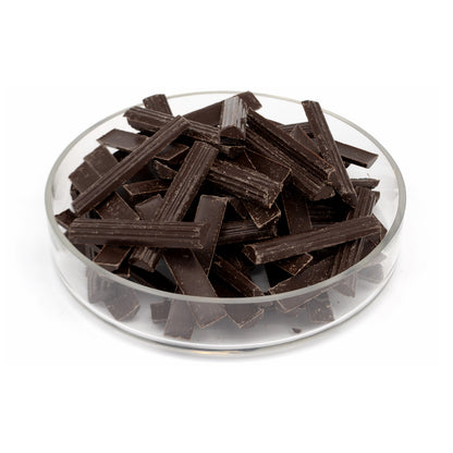 Valrhona chocolate batons piled in a clear glass dish on a white background