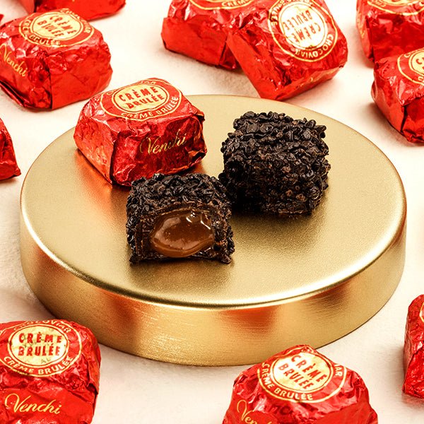 Dark chocolate truffles on a gold plate with red 'Creme Brulee' and 'Venchi' chocolate wraps.