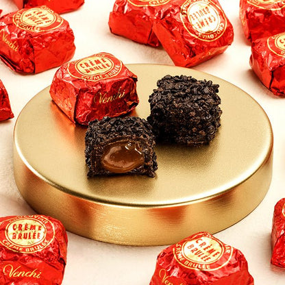 Dark chocolate truffles on a gold plate with red 'Creme Brulee' and 'Venchi' chocolate wraps.